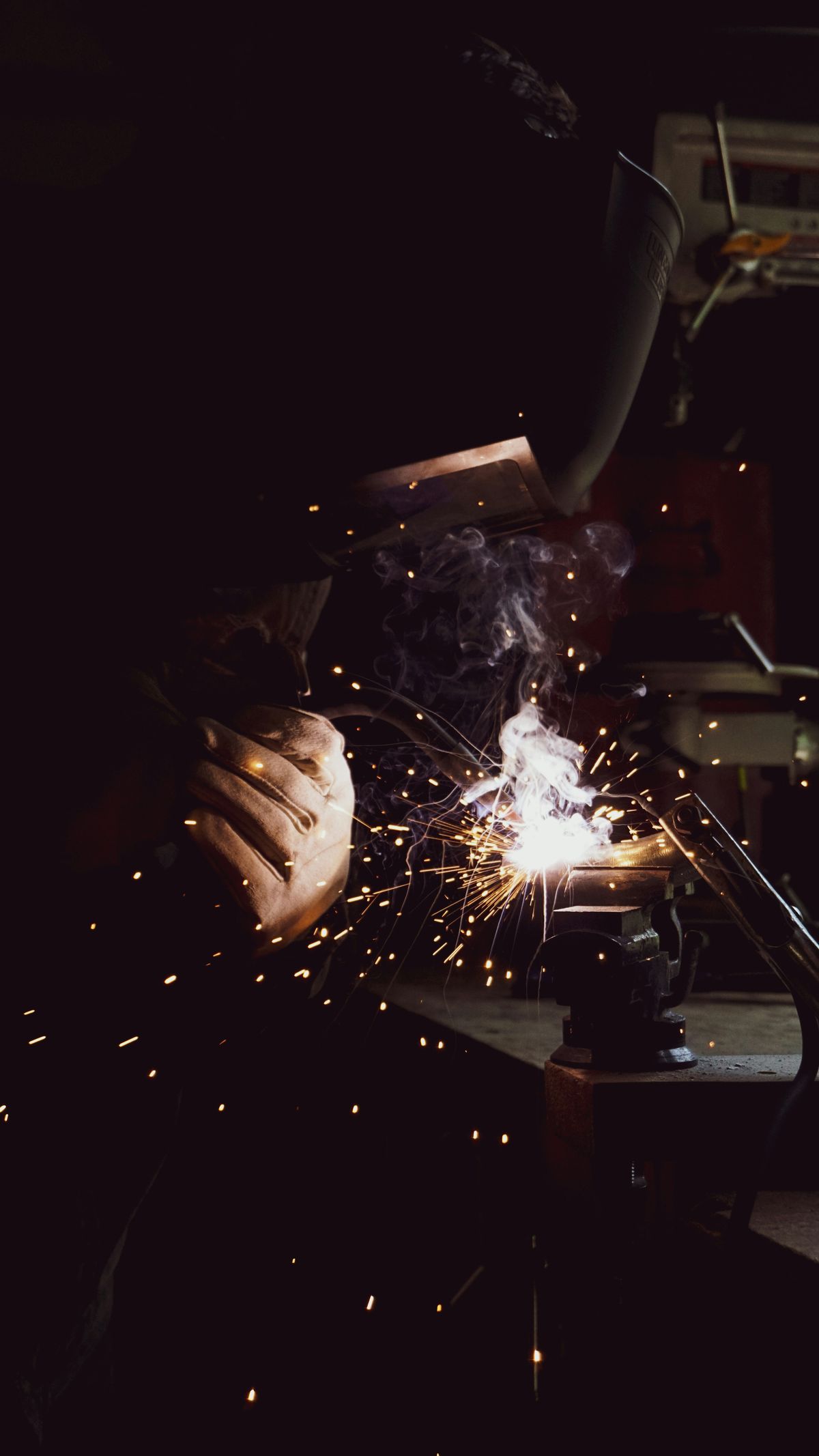 Welder joining metal in a dark shop, sparks flying