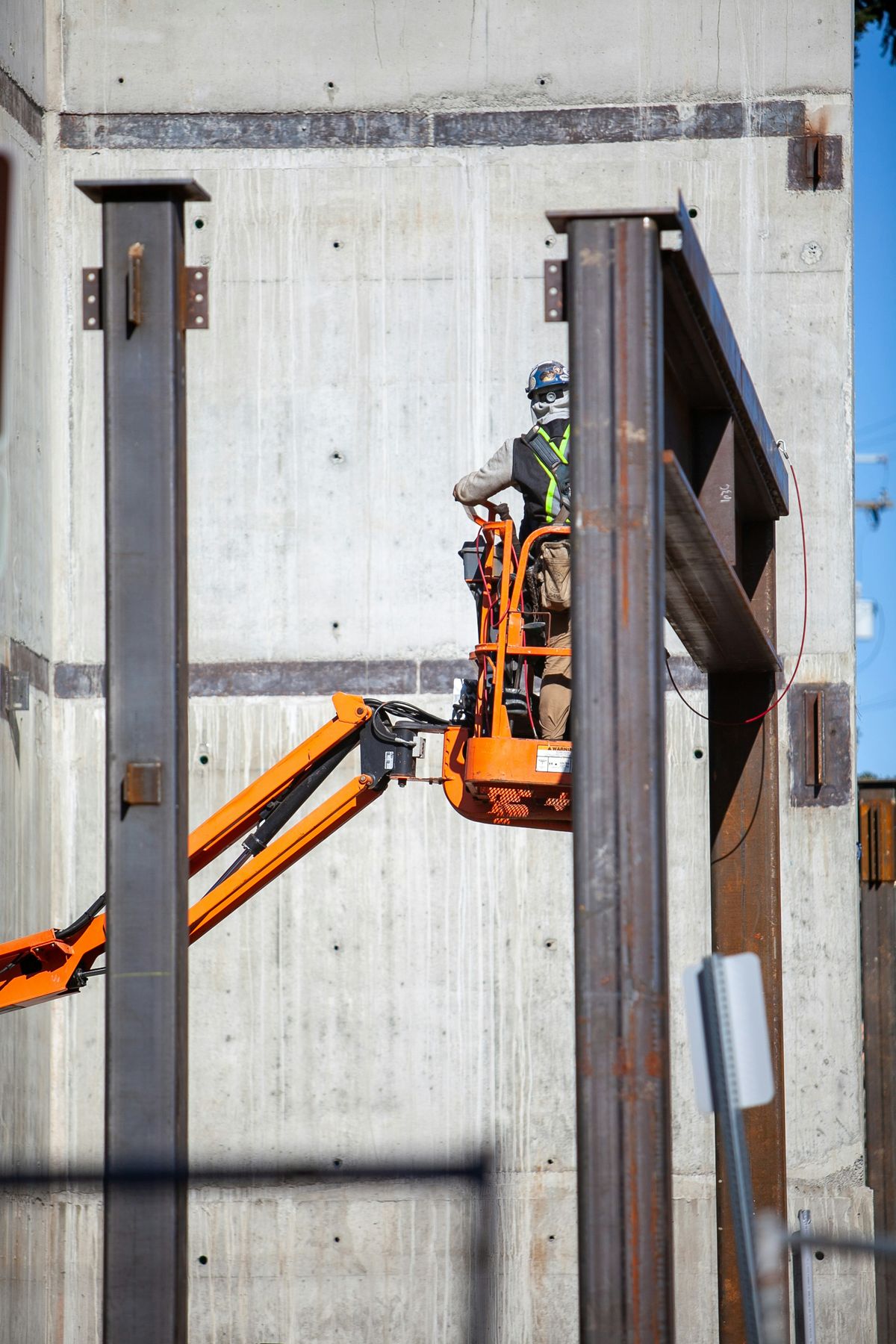 Installer in a hard hat working from a boom lift against a concrete facade